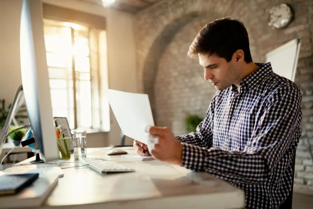 Business owner reviewing EOFY checklist, invoices, payroll, and expenses