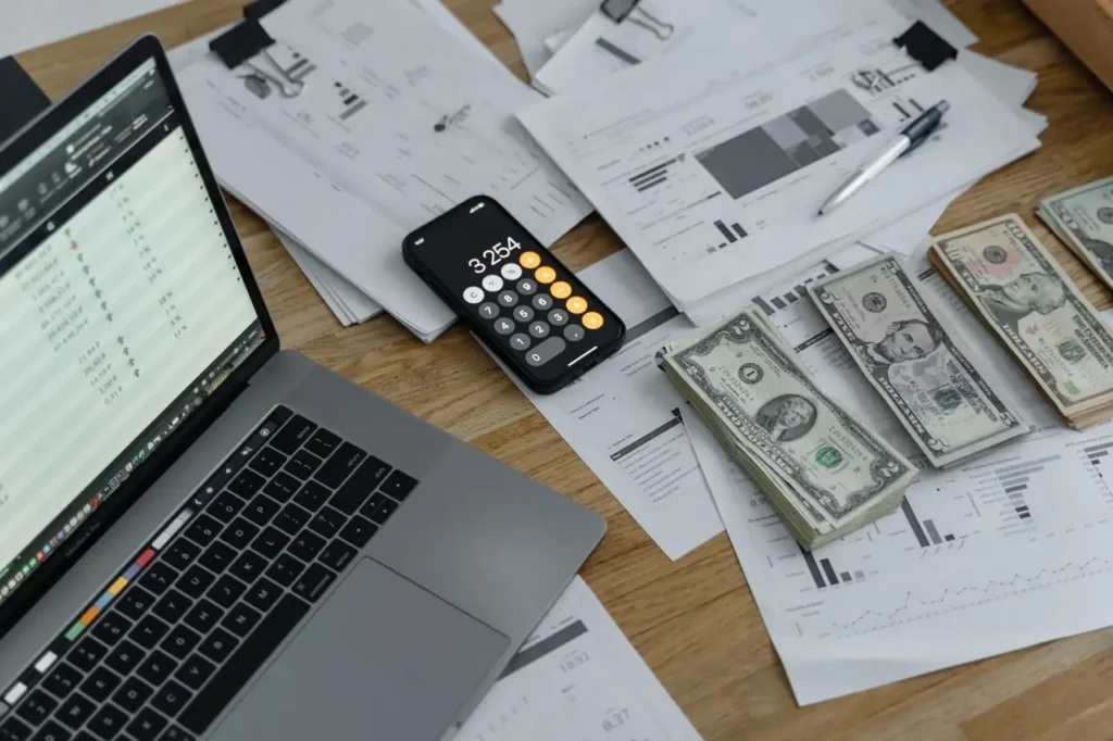 Business financial documents and calculator used for payroll cash flow planning 