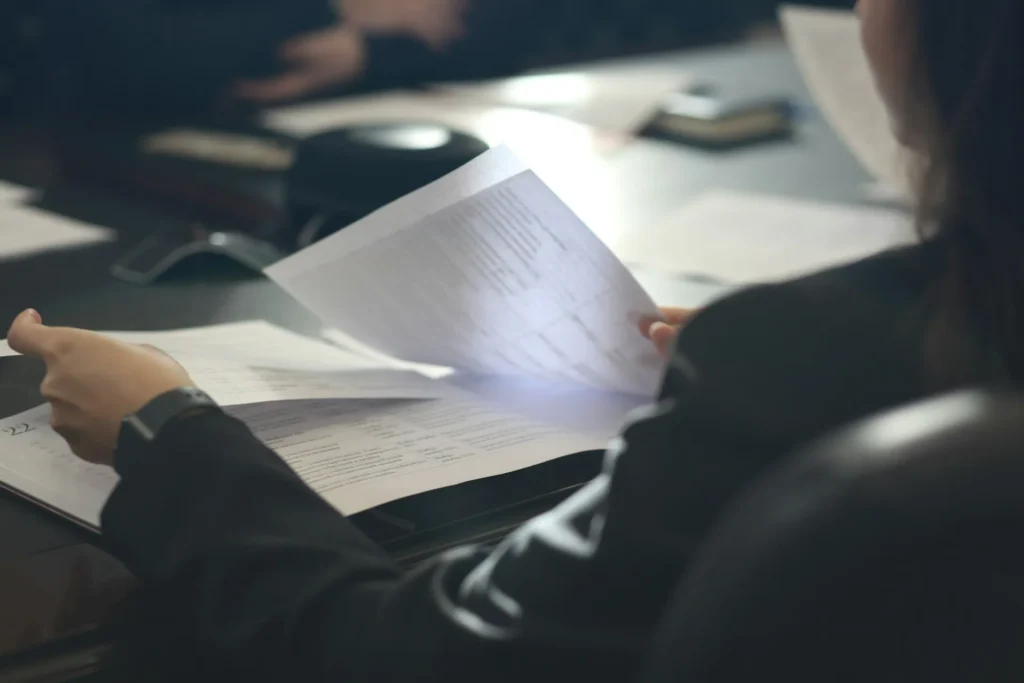 Accountant reviewing client paperwork at a desk beside a laptop, showing the document load accounting document management software is built to organise.
